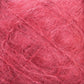 The close-up reveals a dense network of intertwined fibers in shades of reddish-pink, forming an abstract pattern. The texture is coarse yet slightly fuzzy, reminiscent of the luxurious feel characteristic of Caledonian Dye Works' Victorian Brushed Mohair Yarn in Large Skein. Various hues of red and pink are visible throughout the image.