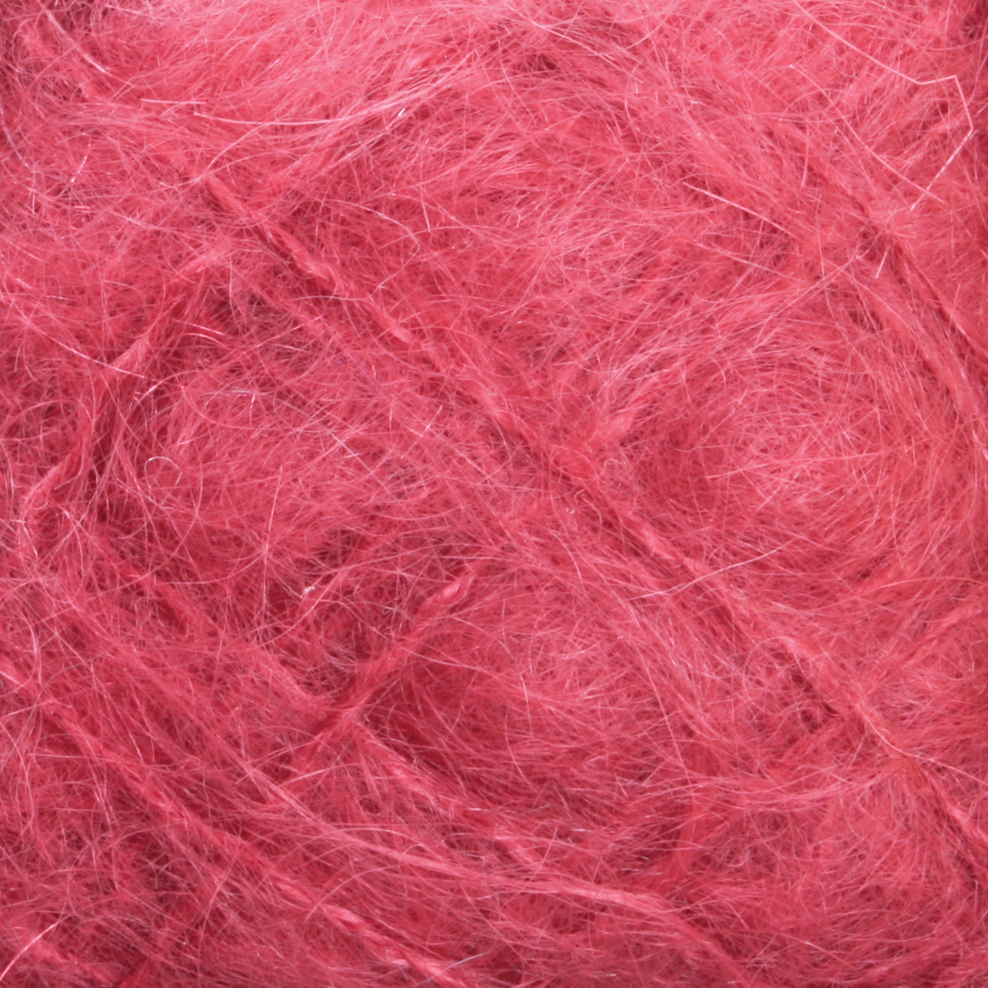 The close-up reveals a dense network of intertwined fibers in shades of reddish-pink, forming an abstract pattern. The texture is coarse yet slightly fuzzy, reminiscent of the luxurious feel characteristic of Caledonian Dye Works' Victorian Brushed Mohair Yarn in Large Skein. Various hues of red and pink are visible throughout the image.