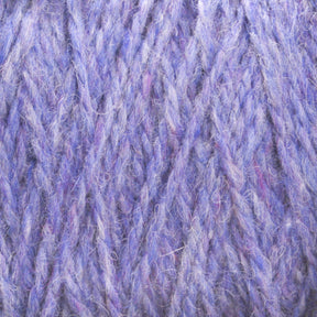 Close-up of lavender-colored Harrisville Highland - Cones yarn from Harrisville Designs, showcasing its soft, woolly texture. The intertwined threads create a thick and fuzzy appearance with subtle variations in shades of purple, enhanced by the natural spinning oils in the unscoured yarn.