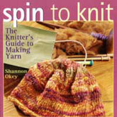 The image displays the cover of "Spin to Knit The Knitter's Guide to Making Yarn" by Shannon Okey, a book published by Golden Peak Media. The cover art features a partially knitted multicolored item with knitting needles and spinning equipment set against a pink backdrop.