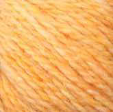 Close-up of a ball of Harrisville Designs' Peace Fleece yarn showcasing its soft, fuzzy texture and marbled pattern in shades of yellow and light orange. The individual strands, crafted from a blend of wool and mohair, are visible, intricately intertwined to create a consistent, thick rope-like appearance.