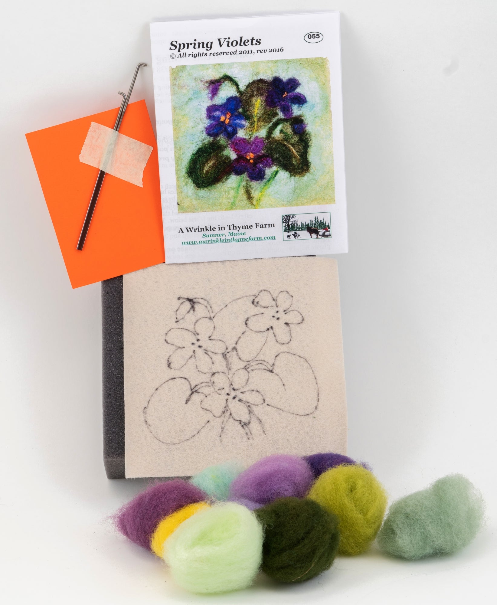 The felting kit labeled "Thyme Tile Felting Kit" from A Wrinkle in Thyme Farm provides an example of the finished product: a beautifully crafted thyme tile. Ideal for beginner felters, this needle felting kit includes various colored wools, a felting needle taped to an orange foam pad, and a template with a sketched outline of the design.