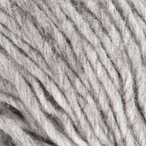 A skein of Jöklalopi (Bulky Lopi) from Berroco, Inc. is coiled in a loose bundle against a white background. The thick, gray yarn appears soft and slightly fuzzy, making it perfect for knitting chunky winter sweaters or other cozy projects in natural shades.