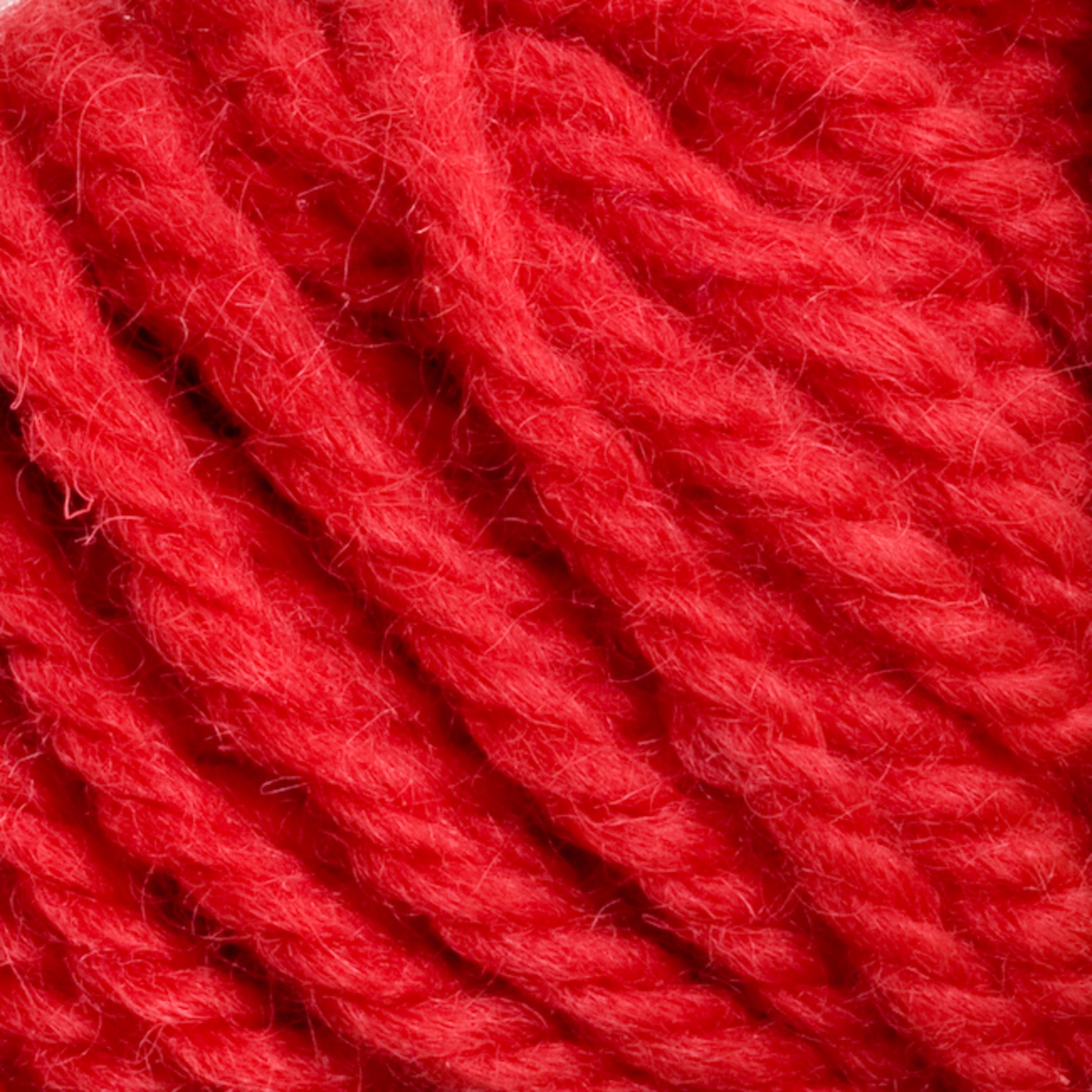 Close-up of vibrant Halcyon Yarn Classic Rug Wool | Skein in a rich red hue with thick, textured strands intertwined. The fibrous material from Caledonian Dye Works appears soft and slightly fuzzy, making it suitable for knitting or crocheting. Hand-dyed by skilled weavers, the image highlights the intricate details and rich color of this exceptional yarn.