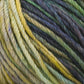 Close-up of a ball of multicolored Malabrigo Rios yarn by Malabrigo Yarn, showcasing kettle-dyed colors in shades of green, yellow, blue, and gray intertwined in twisted strands, resulting in a soft and textured appearance.