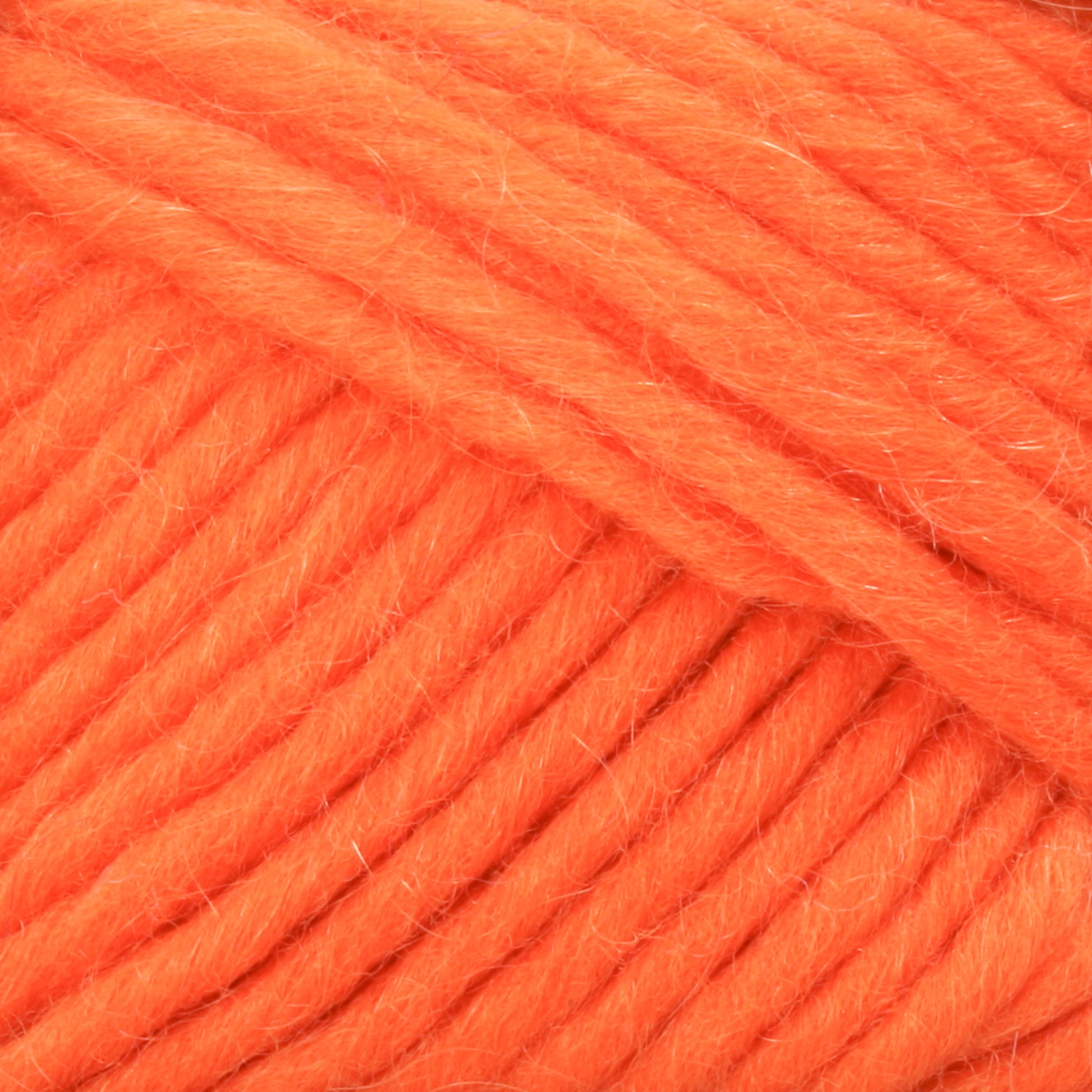 Close-up of Lamb's Pride Worsted Yarn by Brown Sheep in a bright orange hue, highlighting the texture of its soft, thick strands. The yarn looks fluffy and well-defined, showcasing its plush and cozy qualities, making it perfect for knitting or crocheting Navajo style weaving projects.