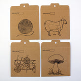 The Halcyon Yarn Interchangeable Needle Cord Envelopes come in a set of four kraft paper envelopes, each labeled "CORD LENGTH." They feature black line drawings of a ball of yarn, a sheep with dotted lines on its body, geometric shapes, and a mushroom. Each envelope has a tab at the top with a small hole for hanging, making them perfect for organizing travel notions or interchangeable cords.