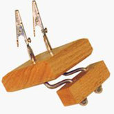 The Shadybrook Fringe Twister from Shadybrook Farm is a wooden device featuring two metal alligator clips attached to flexible arms. The base comprises two wooden blocks connected by a metal spring. This fringing gadget serves as a helping hand tool, commonly used for holding small objects in place while making rugs or scarves.