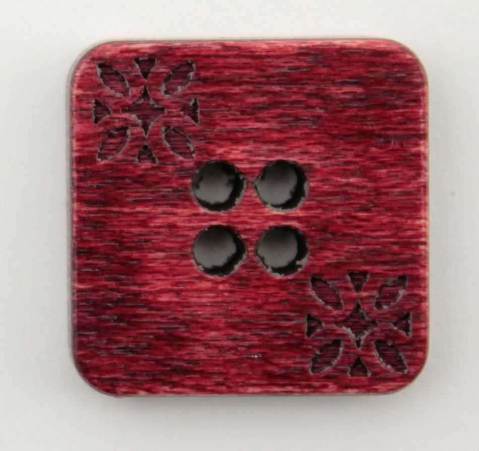 The Wood Square 3/4" Button by Buttons Etc. is a square, dark red button with softly rounded corners and four central holes forming a diamond shape. It features two identical floral patterns etched on opposite corners, and its surface has a wood-like texture with a slightly glossy finish, making it one of the more unique square wooden buttons available.