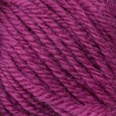 Close-up of Halcyon Deco Rug Wool in magenta or dark pink, 100% wool yarn from Caledonian Dye Works, showcasing its soft texture and twisted strands. The detailed image highlights the fibrous nature and gentle sheen of this versatile yarn, indicating its quality for knitting or crochet projects.