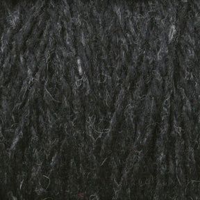 Close-up image of a dark grey Harrisville Designs' Harrisville Highland - Cones yarn showing its thick, textured fibers intertwined. The unscoured yarn appears soft and slightly fuzzy, with variations in the shade of grey, giving it a mottled appearance.