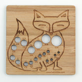 The Never Not Knitting Animal Needle Gauge is a wooden knitting needle gauge shaped like a fox, crafted from laser-cut bamboo. This gauge features multiple circular holes labeled with sizes ranging from 2.00 mm to 15.00 mm, and etched details on the face, body, and tail accentuate its design. The bottom is inscribed with "katrinkles.com"—an ideal tool for Animal Needle Gauges enthusiasts.