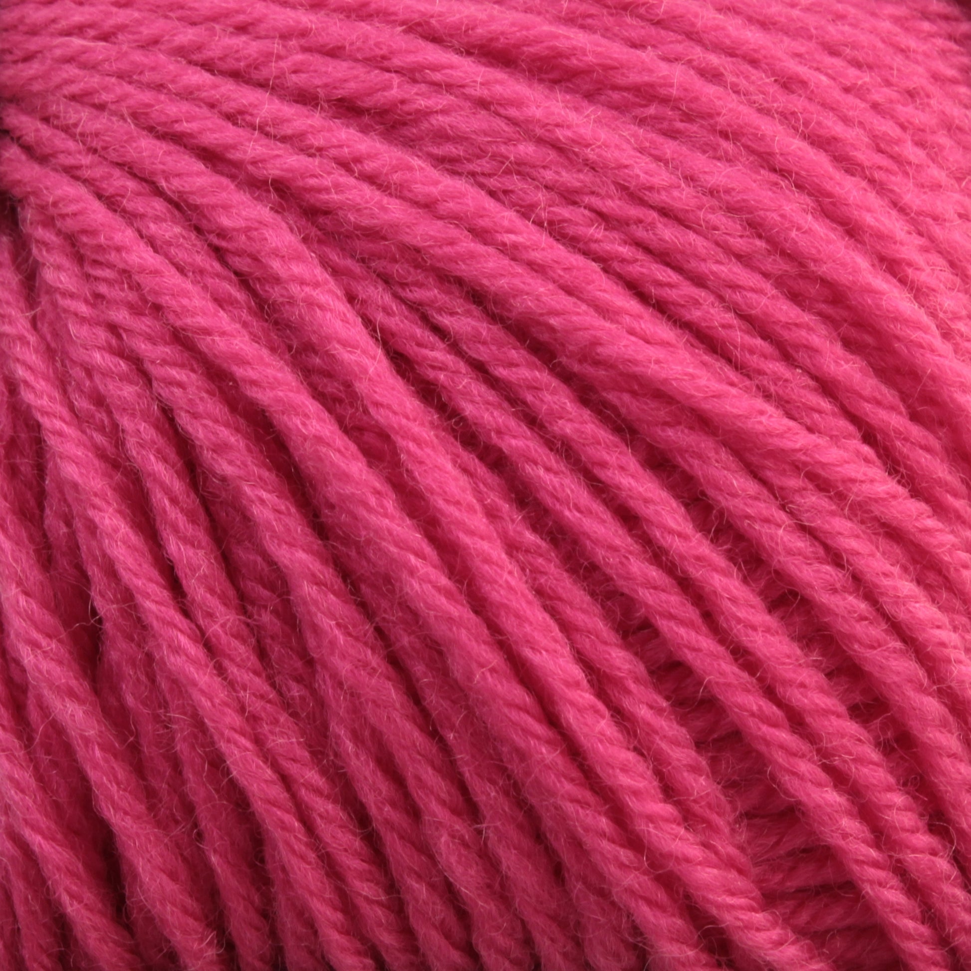 Close-up image of a ball of soft, pink Baby Blatt yarn by Anny Blatt, showing the texture of the intertwined strands. The yarn appears to be loosely twisted and has a matte finish with fine fibers visible on the surface. This machine washable, fingering weight yarn by Essentially Felt Studio & Fine Yarn is perfect for delicate projects.