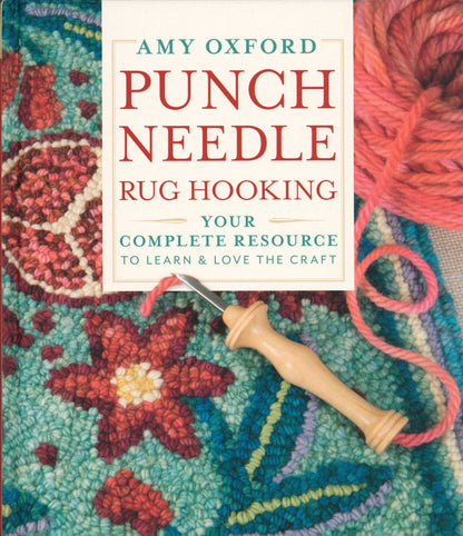 The book cover for "Punch Needle Rug Hooking: Your Complete Resource to Learn & Love the Craft" by Amy Oxford, published by Schiffer Publishing Co., features a punch needle tool on a vibrant hooked rug with a floral pattern. A skein of yarn is displayed in the top right corner, making it an ideal guide for craft enthusiasts.