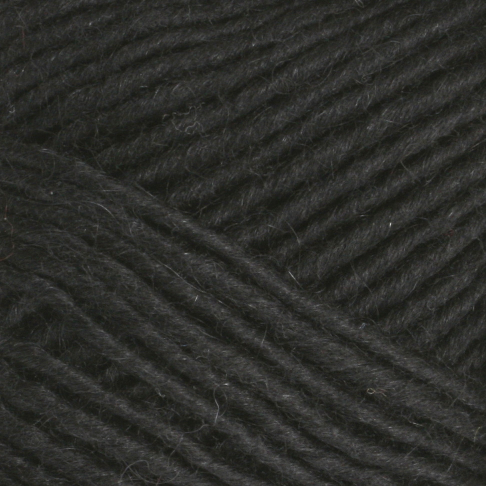 Close-up image of thick, dark gray yarn, tightly coiled and intertwined. The texture appears soft and slightly fuzzy, indicative of natural fibers such as Brown Sheep's Lamb's Pride Worsted Yarn. The even, parallel strands suggest quality yarn suitable for knitting or felting projects.