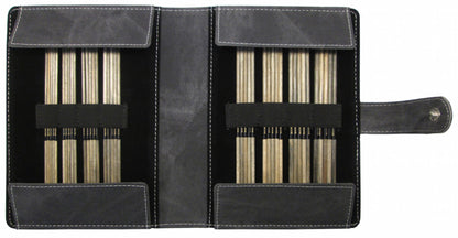 An open black leather case from Knitting Fever / Euro Yarns showcases a meticulously arranged Lykke Double-Point Knitting Needle Set, 6", featuring metal or wooden needles held securely by elastic bands. The case is enhanced with white stitching and includes a snap-button closure on the right side, along with the assurance of a lifetime guarantee for added peace of mind.