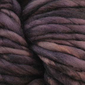 A close-up of thick, multi-colored Malabrigo Yarn Rasta in shades of brown, purple, and black reveals a soft and fuzzy texture. The image captures the intertwined strands of super bulky yarn, highlighting their dense and woolly appearance—perfect for quick-to-knit projects.