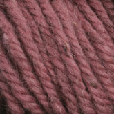 Close-up of thick, textured yarn in a dusty rose color. The fibers appear soft and slightly fuzzy, with the yarn strands twisted together tightly. Ideal for rug weavers, this Halcyon Yarn Classic Rug Wool from Caledonian Dye Works is perfect for creating beautiful, durable pieces.