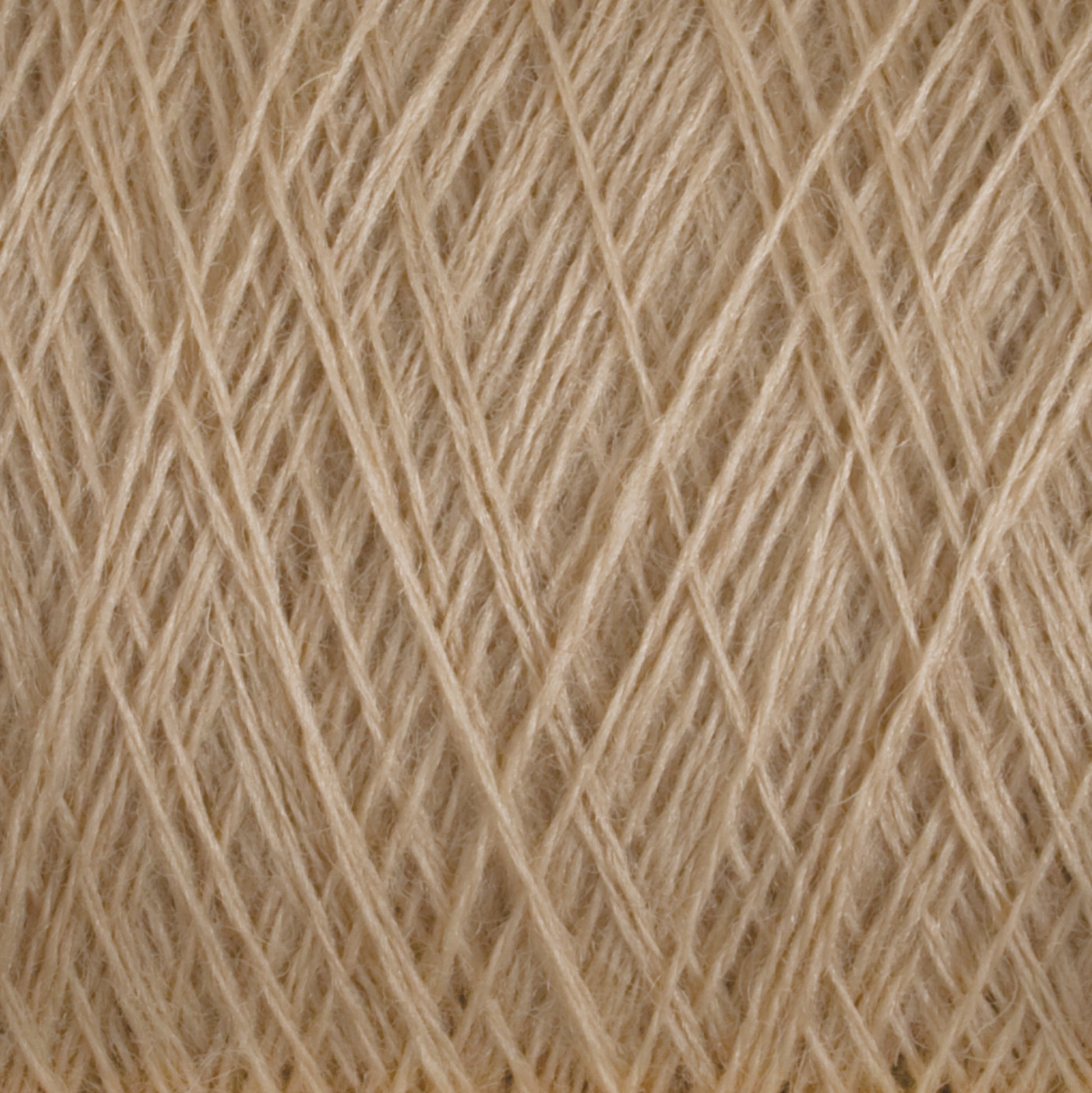 Close-up of a beige ball of Jagger Brothers' JaggerSpun Maine Line 2/20 Yarn | Large Cone. The fibers are tightly wound around each other, creating a dense and textured pattern. The yarn appears smooth and slightly glossy, with an intricate web of intersecting strands.