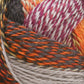 Close-up image of a thick Zauberball Crazy Sock Yarn ball by Skacel, featuring a colorful mix of intertwined fibers in shades of orange, brown, gray, white, and magenta. The texture appears soft and woolly, with color changes creating a vibrant, dynamic pattern from the blend of bright and muted tones.