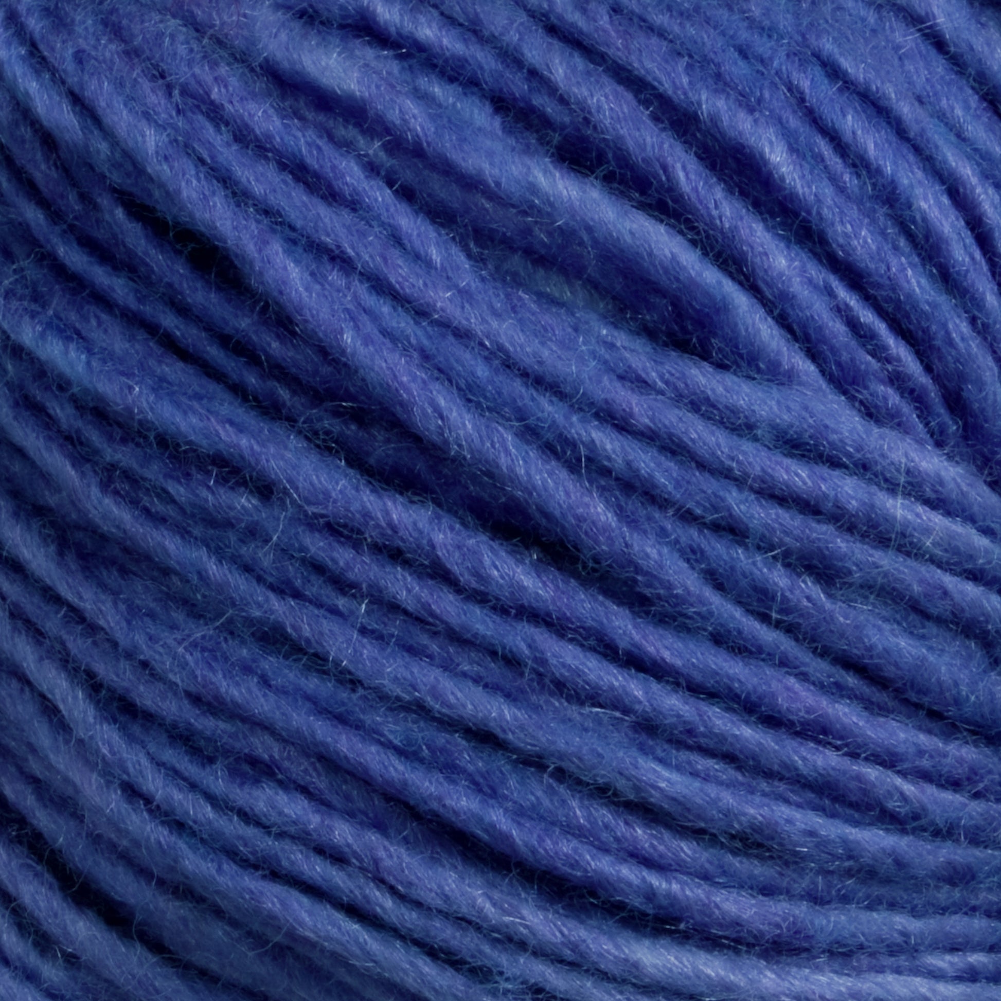 A close-up of a ball of Malabrigo Yarn's Silky Merino. The threads are tightly wound together, showcasing various shades of blue, ranging from light to dark. The texture appears soft and slightly fuzzy, typical of this luxurious blend from Malabrigo.