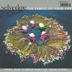 Aerial view of four individuals donning conical hats, arranging water lilies in a circular formation while seated in a lake. The image adorns the cover of Selvedge - Issue 106: Identity, featuring the text "The Fabric of Your Life" at the top and "Make Our Stories Part of Your Story" at the bottom, celebrating textiles and fashion.