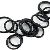 An array of Bryson Rubber Ring Markers from Bryson Distributing, Inc. are casually arranged on a white surface. The ebony-colored markers are accompanied by various small-sized, flexible rubber O-rings, all circular in shape.