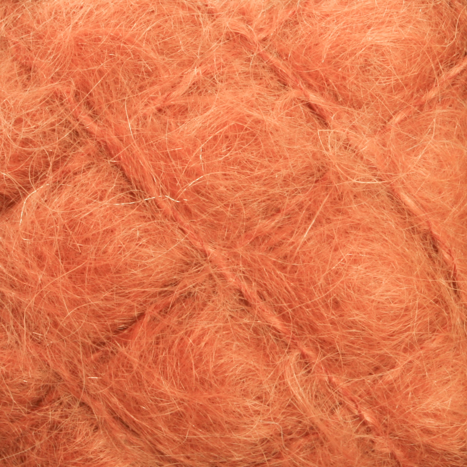 Close-up image of Victorian Brushed Mohair Yarn | Mini Skein by Caledonian Dye Works in a warm, peachy-orange color. The soft, fluffy material has a wispy and delicate texture that resembles fine strands of luxurious mohair. The surface appears tangled and intertwined.