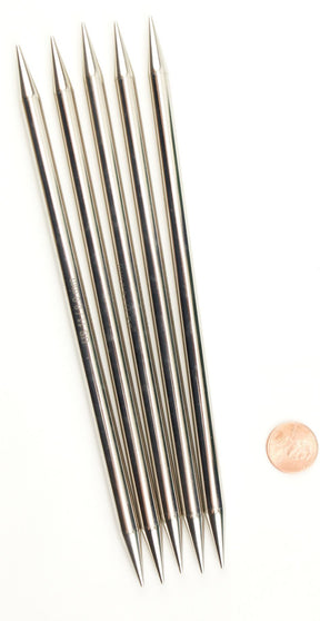 Six high-quality Nova Platina Double-Point Knitting Needles by Accessories Unlimited are arranged in a fanned-out formation on a white background. A penny is placed beside them for scale.