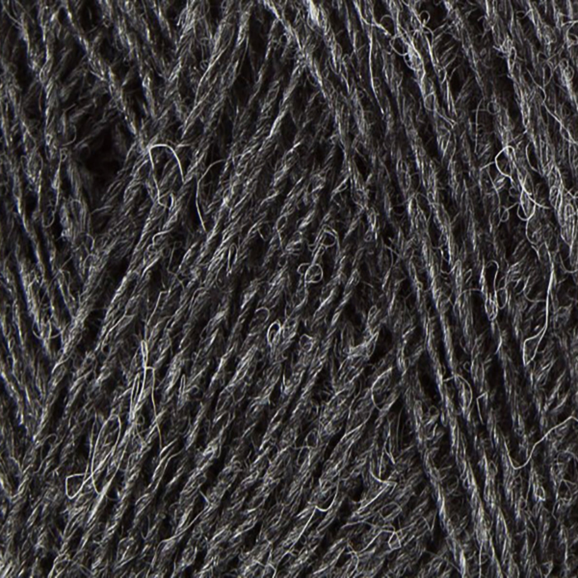 Close-up image of dark grey Einband Lopi woolen yarn fibers intertwined, showing texture and slight variations in shades of grey. The surface appears soft with a few stray fibers sticking out, perfect for intricate lace knitting projects. This high-quality product is brought to you by Berroco, Inc.