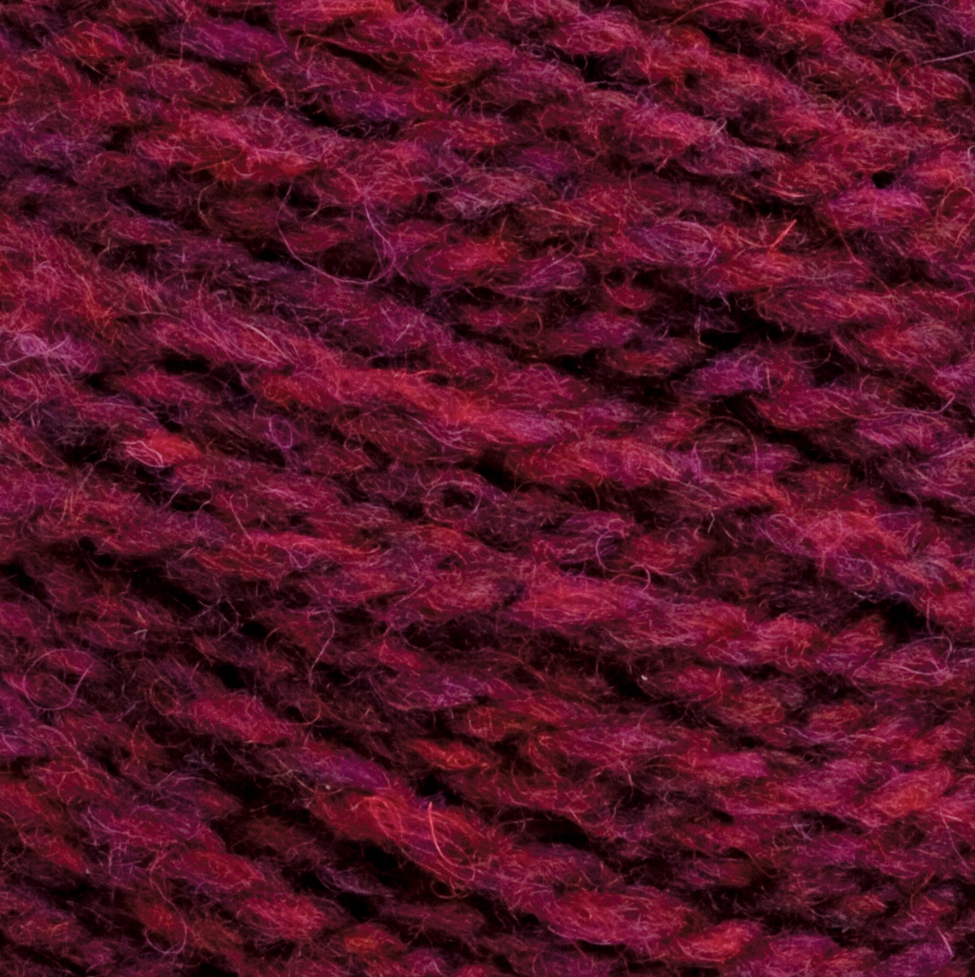 Close-up image of deep magenta and dark purple **Harrisville Designs Harrisville Highland - Cones**, showcasing a tightly woven texture with visible fibers and strands. The colors blend smoothly, creating a rich, cozy look ideal for knitting or crocheting projects.