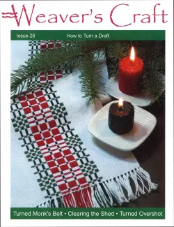 The cover of Plain Tabby Press’s Weaver's Craft Issue 26: How to Turn a Draft features a woven cloth with a red and black pattern, accompanied by red and black candles set on white saucers and festive pine boughs. The text on the cover highlights various weaving projects, including "How to Turn a Draft," "Turned Monk's Belt," "Clearing the Shed," and "Turned Overshot.