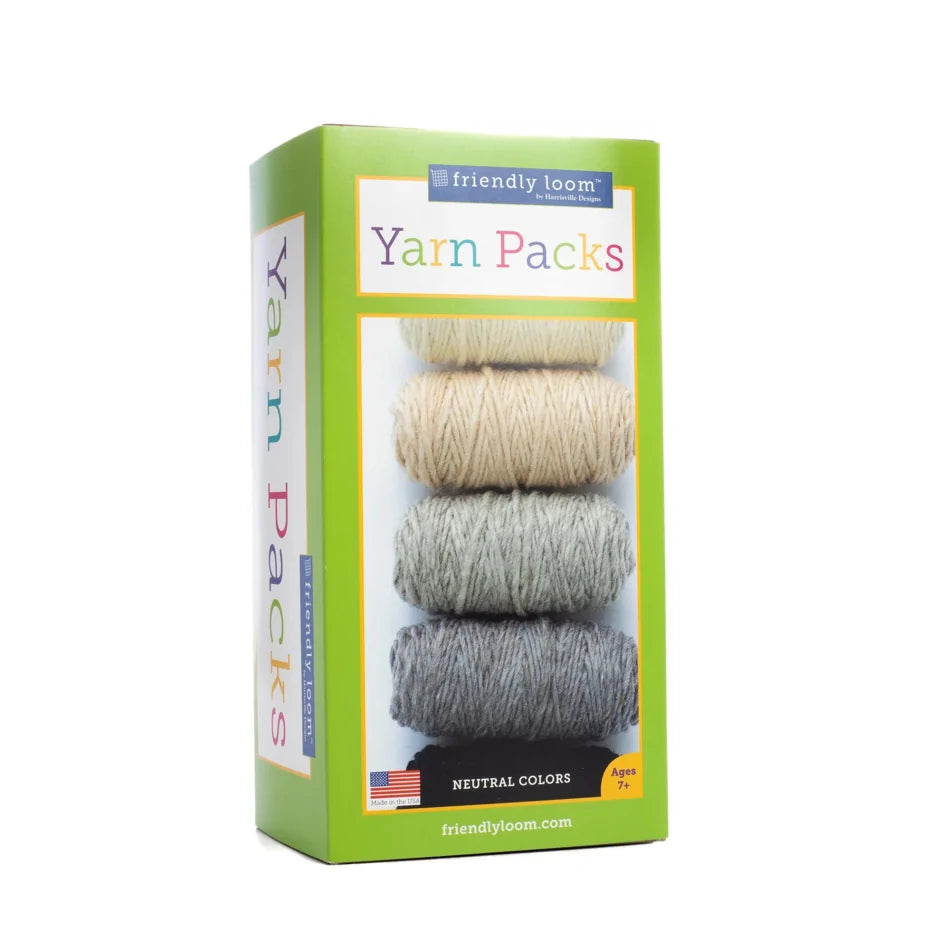 A package of Friendly Loom Lap Loom Yarn Pack featuring a stack of six balls of 100% wool yarn in neutral colors (beige, light gray, gray, and dark gray). The green packaging with colorful text states it is suitable for ages 7 and up. An American flag is displayed at the bottom.