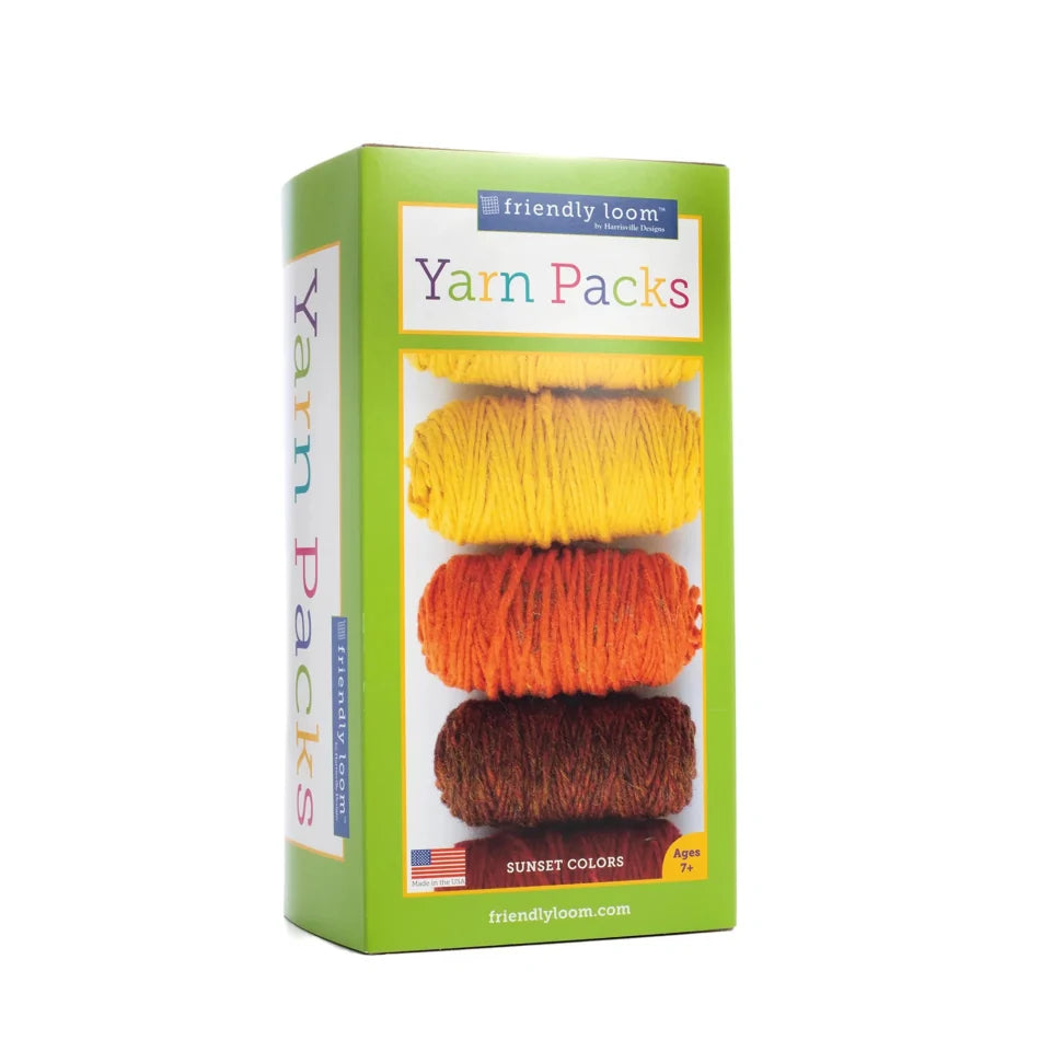 A rectangular box labeled "Friendly Loom Lap Loom Yarn Pack, 6 Balls" containing skeins of 100% wool yarn in yellow, orange, and brown is shown. The package, titled "Sunset Colors," includes designer yarn and is intended for ages 7 and up. The bottom of the box shows a website address: friendlyloom.com.