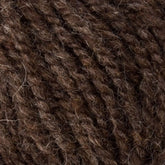 A close-up of Bartlett Maine Wool, Sport Weight Cones by Bartlettyarns reveals its textured, dark brown wool with a homespun appearance. The yarn is thick, slightly fuzzy, and features intertwined strands for a soft, natural look.