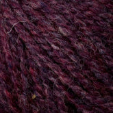 Close-up of Bartlettyarns' Bartlett Maine Wool, Sport Weight Cones featuring textured, twisted yarn in deep burgundy and dark purple hues with scattered lighter fibers for a rich, variegated homespun look.