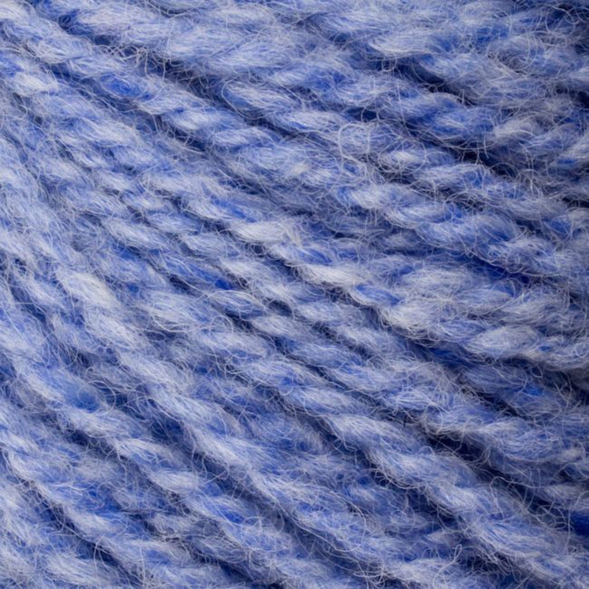 A close-up of Bartlettyarns' Bartlett Maine Wool, Sport Weight Cones reveals soft, textured yarn in light blue and lavender. The intertwined fibers offer a cozy, homespun look that's comforting and inviting.