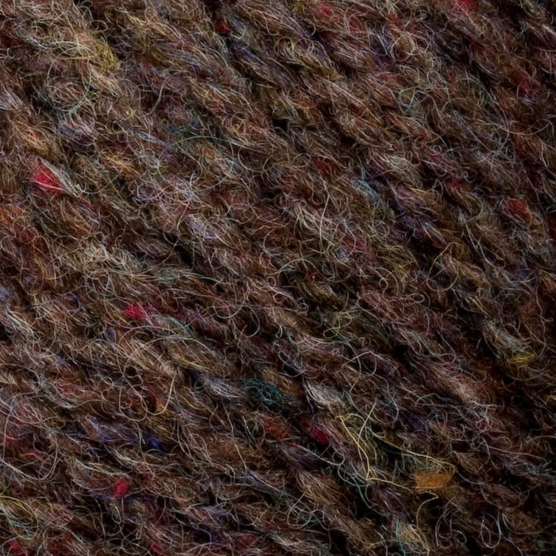 A close-up of Bartlettyarns' Bartlett Maine Wool Sport Weight Cones showcases soft, slightly fuzzy wool with varied strands and subtle multicolored flecks in red, blue, and yellow, enhancing its homespun appearance by highlighting intertwined fibers.