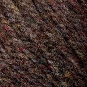 A close-up of Bartlettyarns' Bartlett Maine Wool Sport Weight Cones showcases soft, slightly fuzzy wool with varied strands and subtle multicolored flecks in red, blue, and yellow, enhancing its homespun appearance by highlighting intertwined fibers.