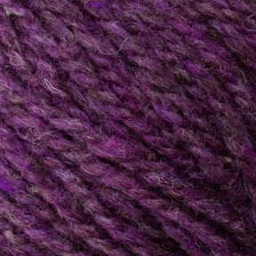 A close-up reveals the Bartlett Maine Wool, Sport Weight Cones by Bartlettyarns, featuring a mix of purple shades. Its soft, homespun look and interwoven fibers create a richly hued surface, ideal for knitting or crafting projects.