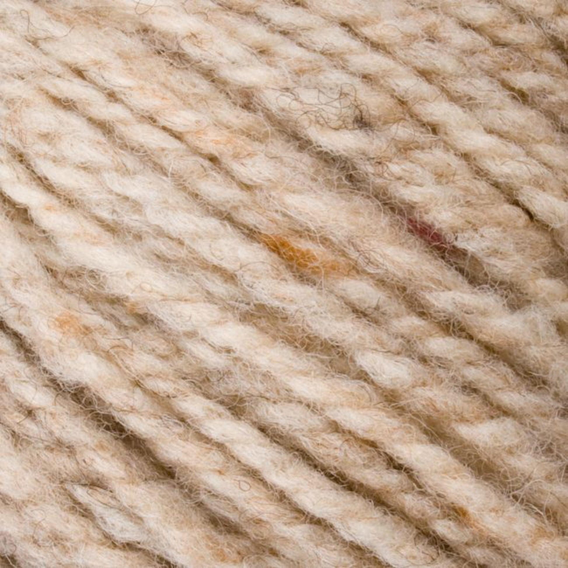 Close-up image of Bartlett Maine Wool, Sport Weight Cones by Bartlettyarns in beige and light brown, highlighting its soft, textured fibers. The yarn has a speckled, homespun look with darker threads woven in.