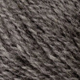 Close-up of Bartlettyarns' Bartlett Maine Wool, Sport Weight Cones, in grey. The yarn blends light and dark strands for a marbled effect with its soft, slightly fuzzy texture creating a cozy homespun look.