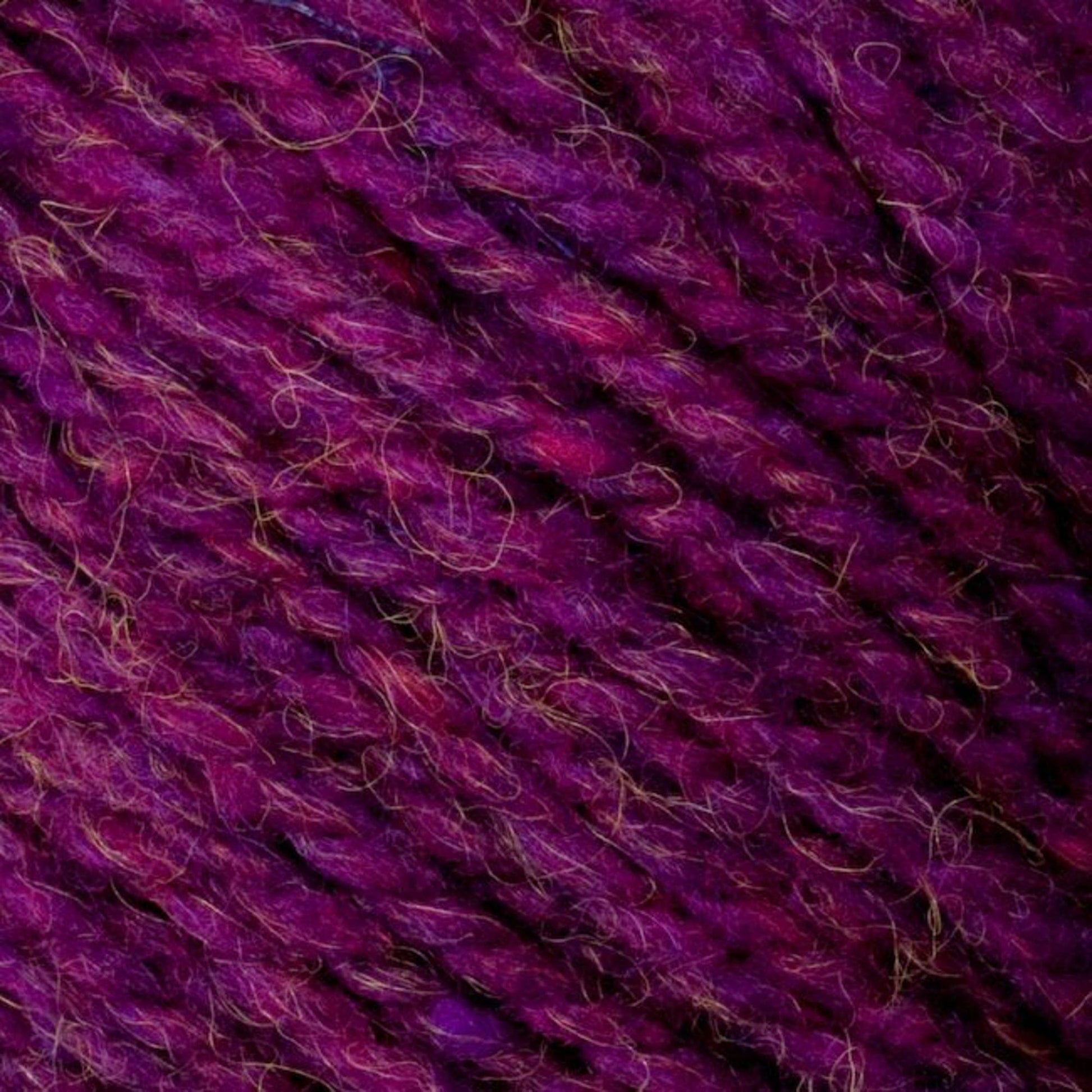 Close-up of Bartlettyarns' Bartlett Maine Wool, Sport Weight Cones in textured purple shades with homespun appearance, magenta hints, and a slightly fuzzy look from small fibers. This thick, soft yarn is ideal for knitting or crocheting projects.